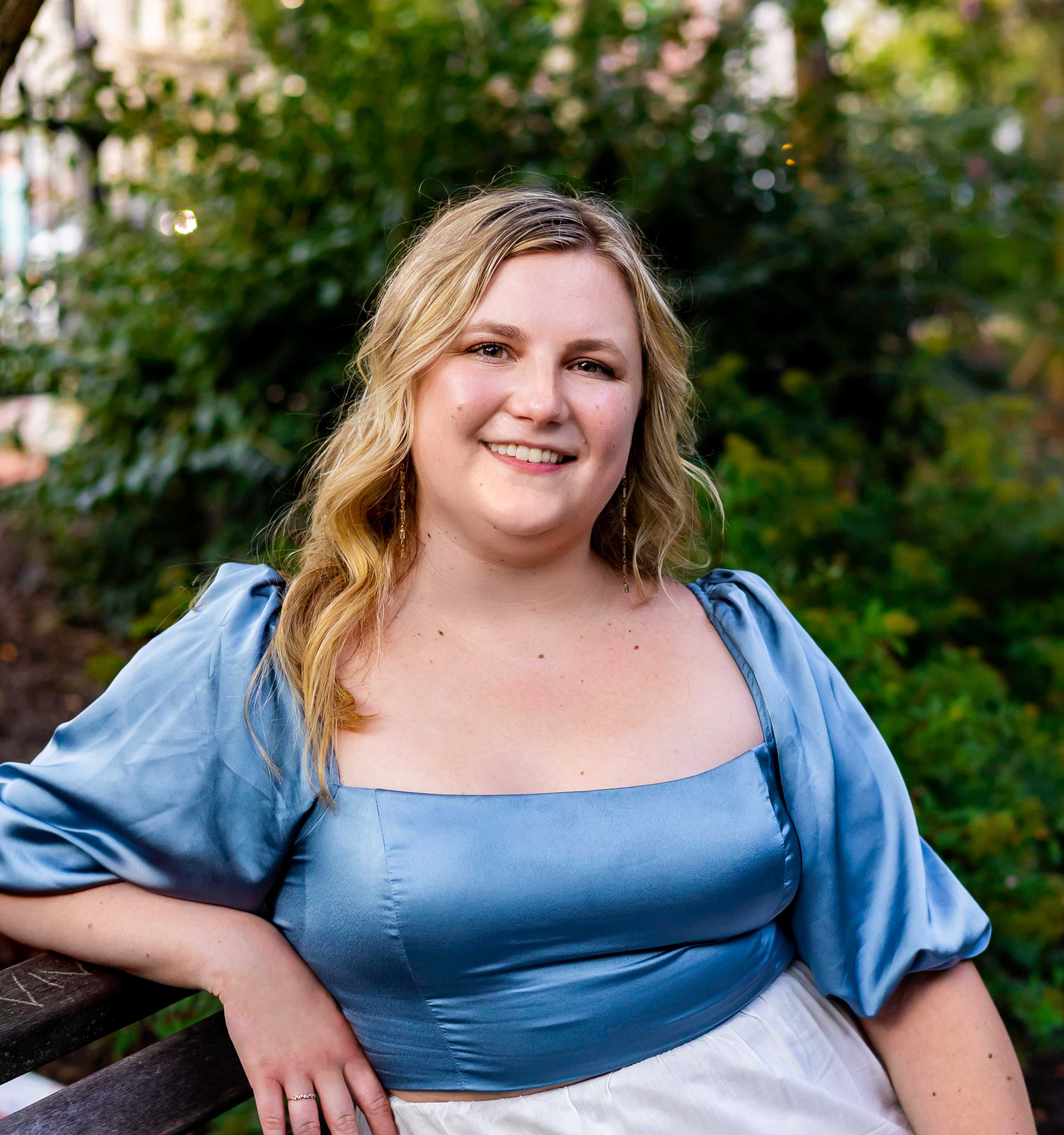 Larisa smiling and sitting on a bench